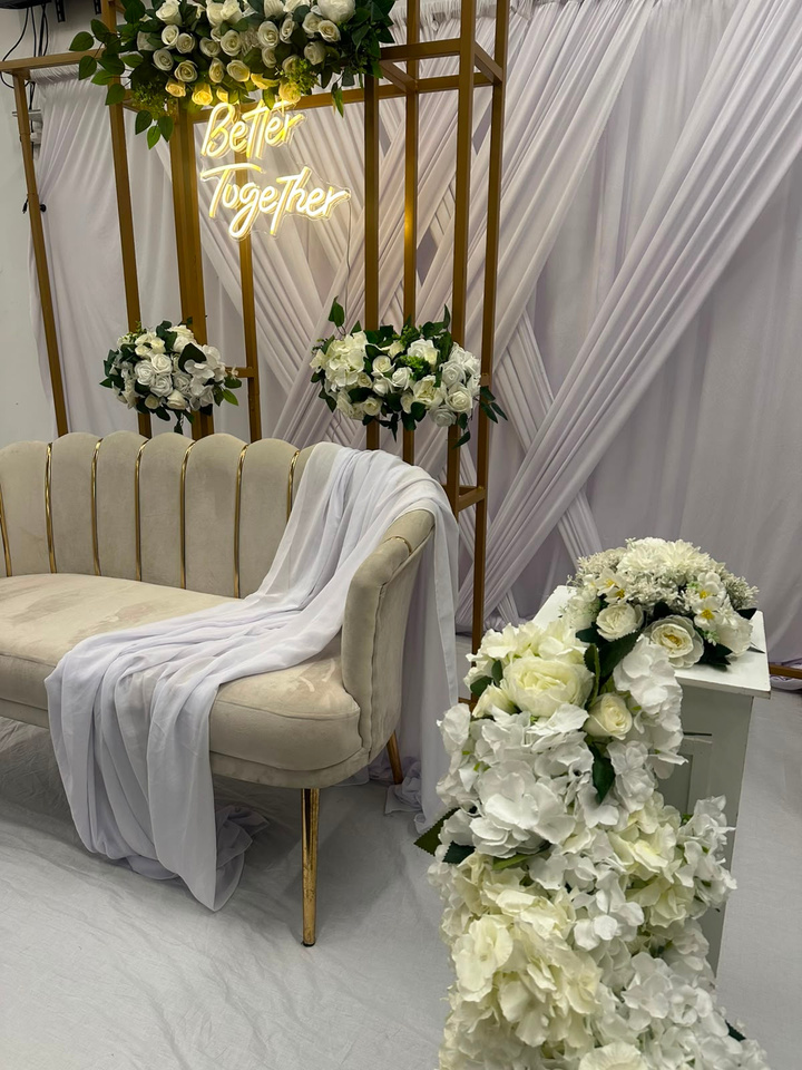Elegant white and gold wedding backdrop with floral arrangements and neon Better Together sign